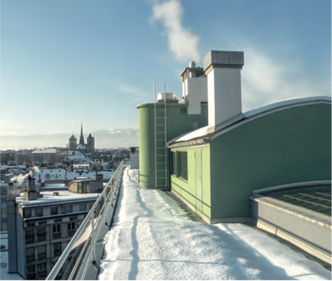Verschneites Dach mit grünen Aufbauten und rauchendem Schornstein, Stadtblick mit Kirchtürmen, Corbusier